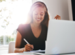 a woman studying in front of a laptop while taking notes