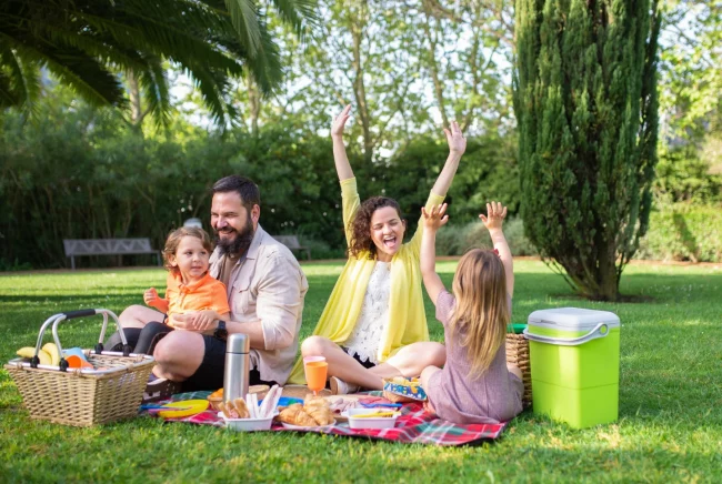 Summer-picnic Parents with two kids having a picnic at the park, laughing and having fun.